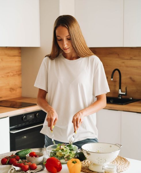 Woman in White T-shirt Holding Stirring Salad in Glass Bowl
